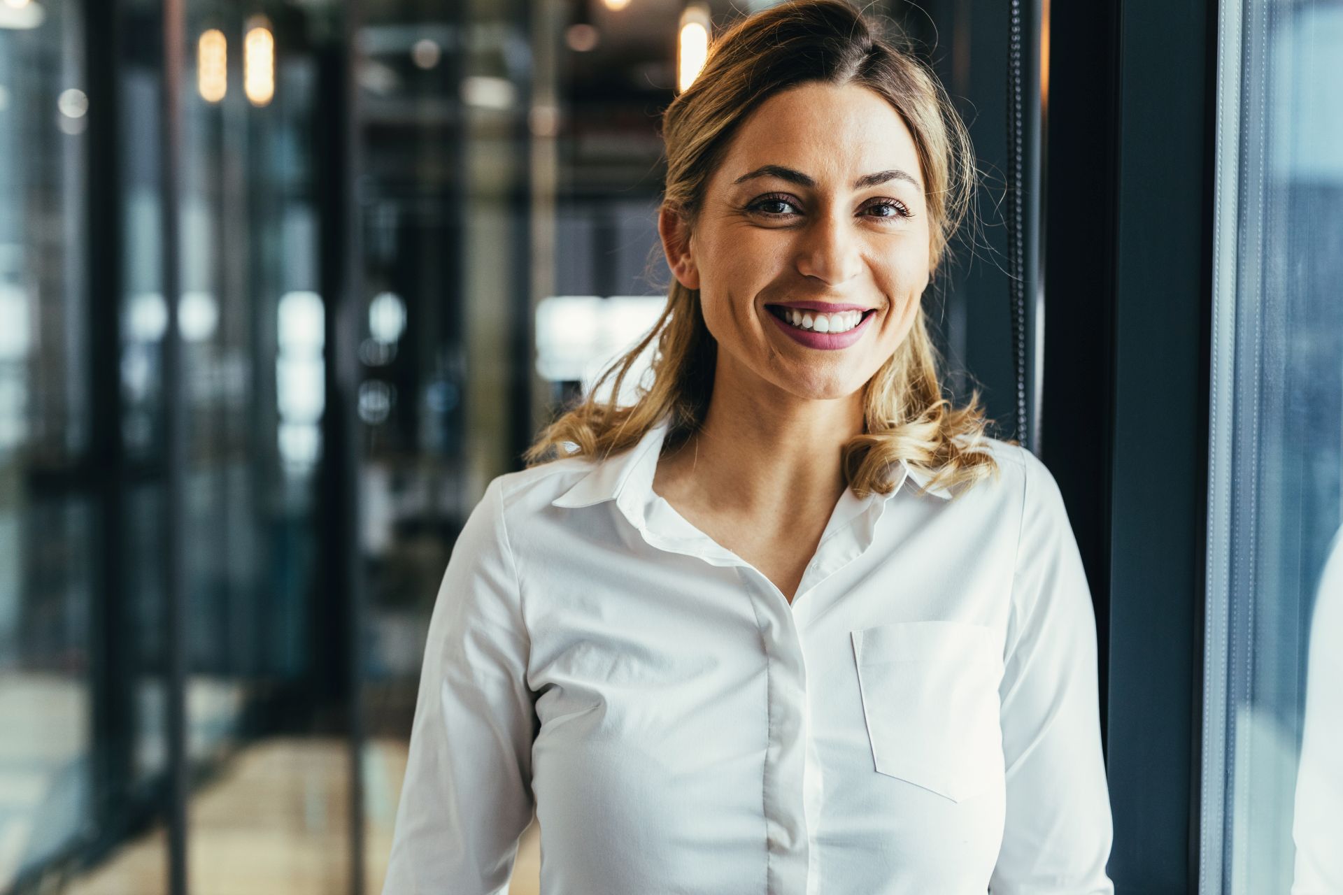Frau im Businesslook lacht in die Kamera.